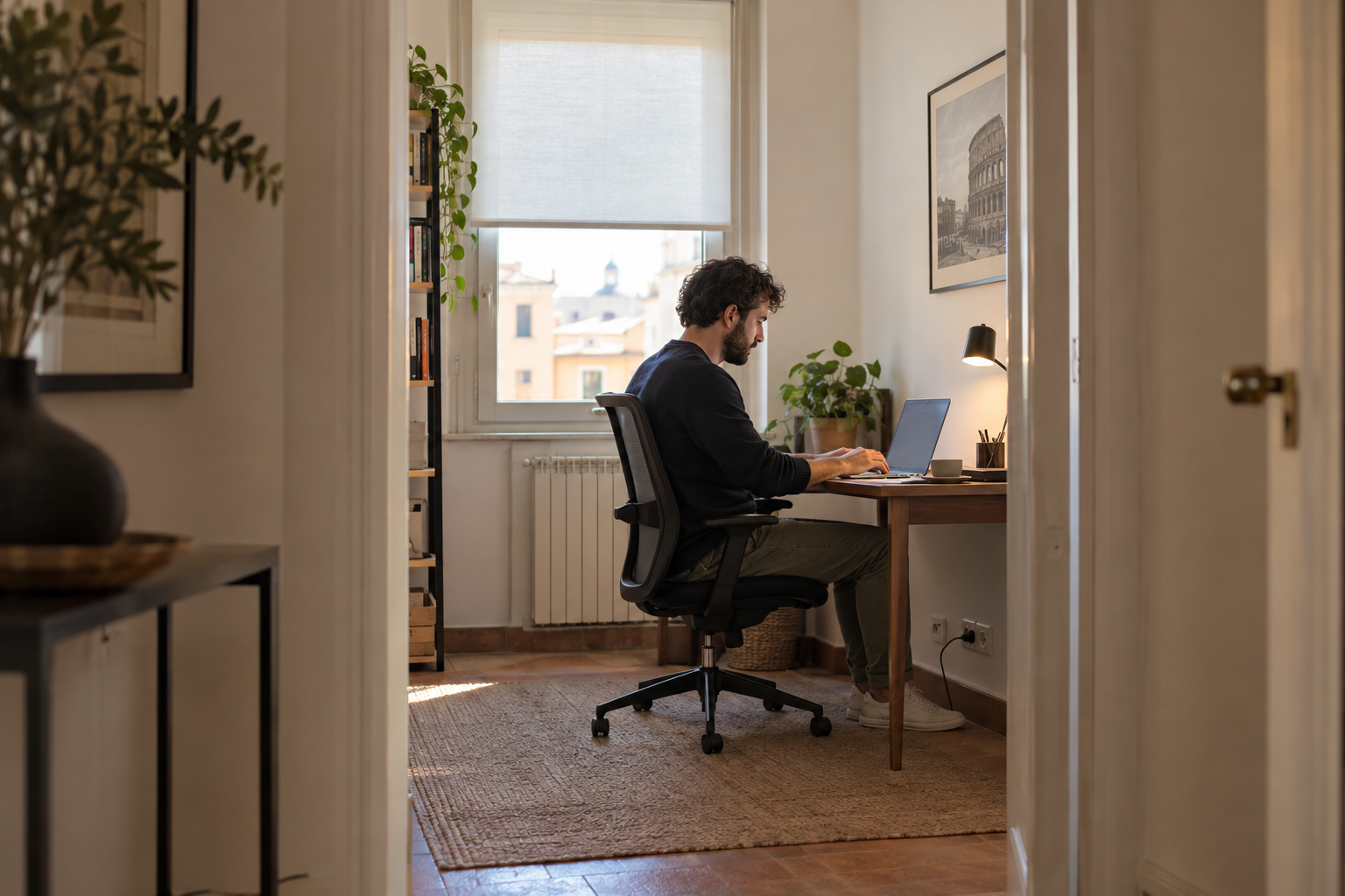 Ospite al lavoro in uno studio separato con scrivania ampia e sedia ergonomica in un appartamento per soggiorni brevi.